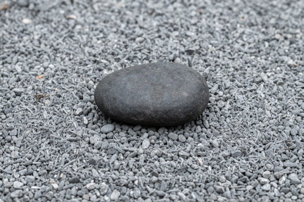 Piedra grabada con trazos sencillos reposando en un jardín zen